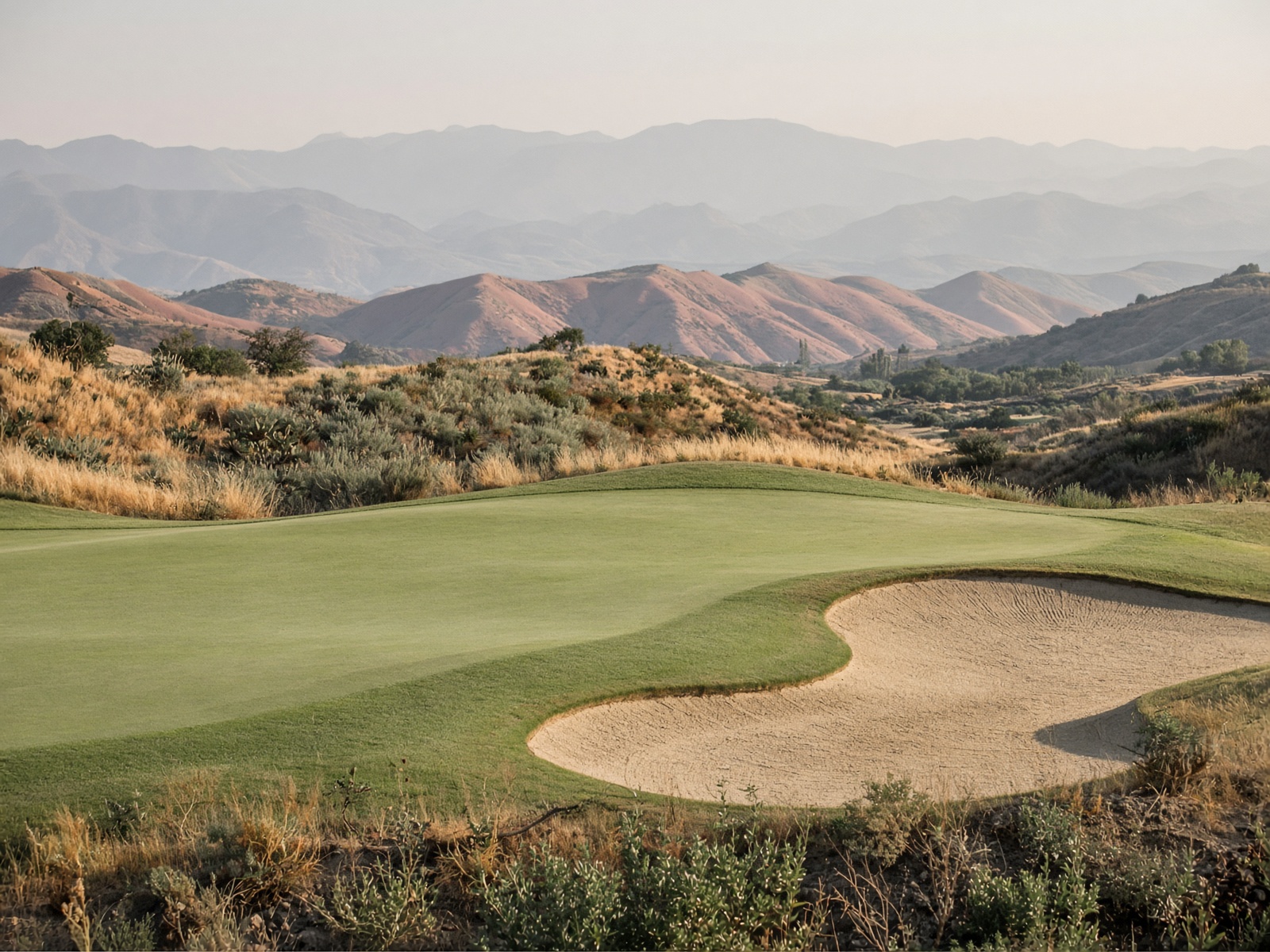 Green and bunker with mountains beyond